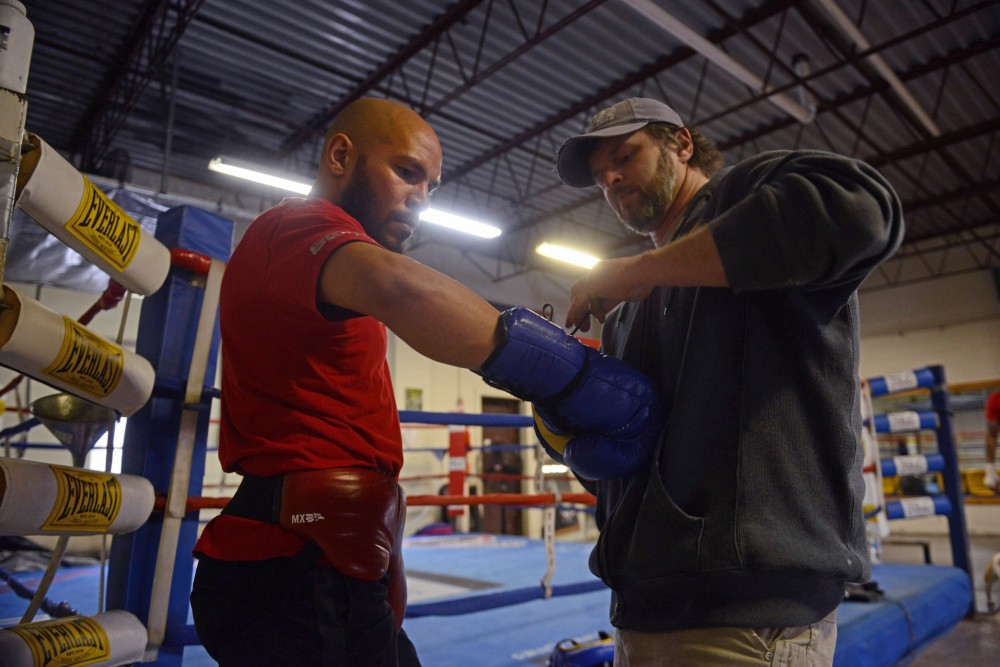 Ron Lyke, right, helps boxer Caleb Truax put on his gloves before sparring against Ronald Mixon at Anoka Coon Rapids Boxing Gym on Tuesday, March 20. 