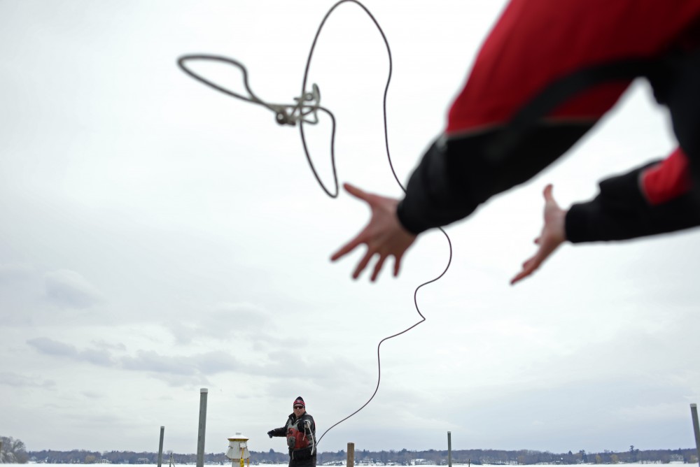 Cappy Capper throws a rope to a sailer to move a boat from dock to dock in preparation for practice. 
