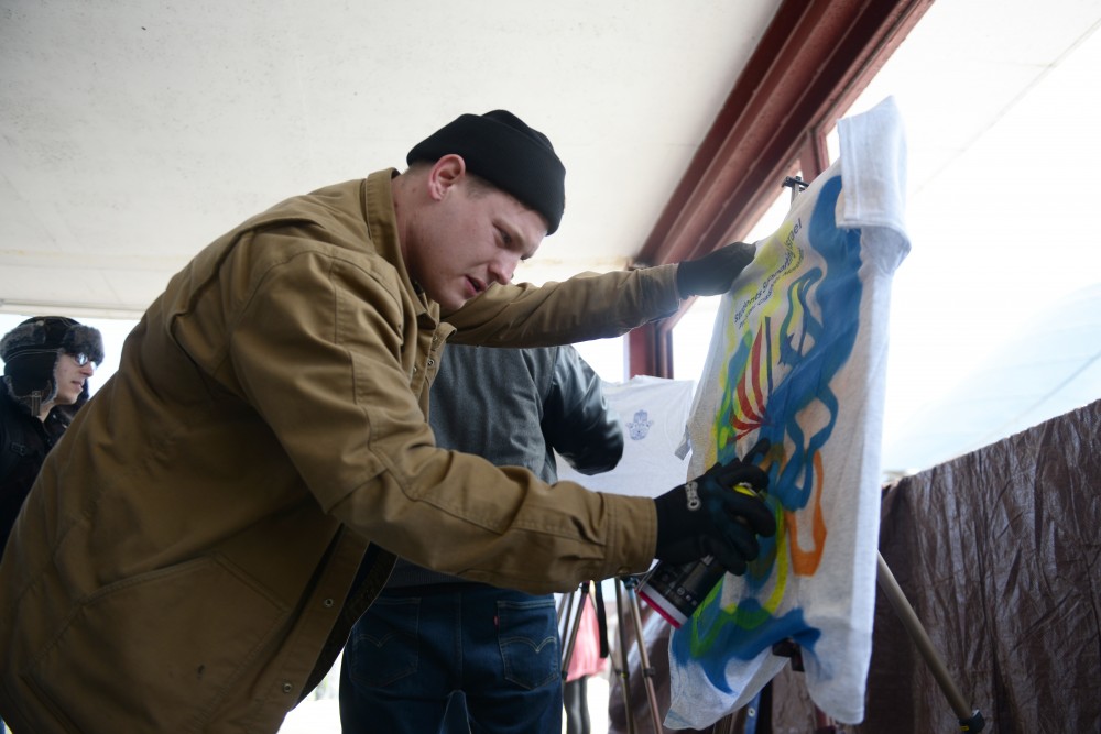Galen Riggs spray paints a free shirt given to students passing by in support of the Students Supporting Israel group, a Pro-Israel international campus movement that supports the State of Israel.
