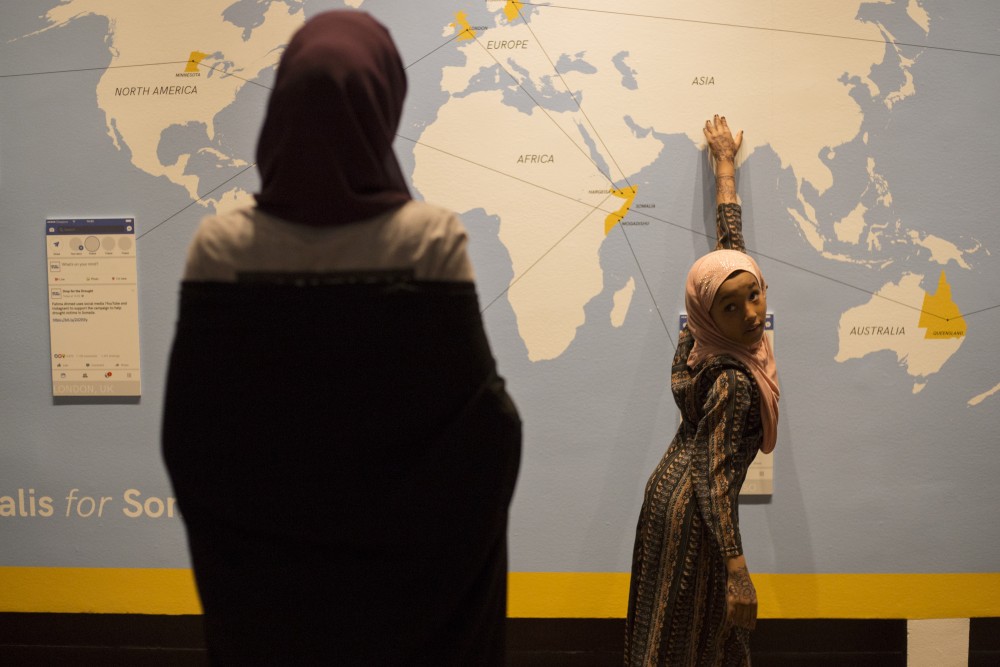 Lima Ahmad, 8, asks her older sister about different countries on a map at the History Centers new Somalis + Minnesota exhibit on Saturday, June 23 in Saint Paul.