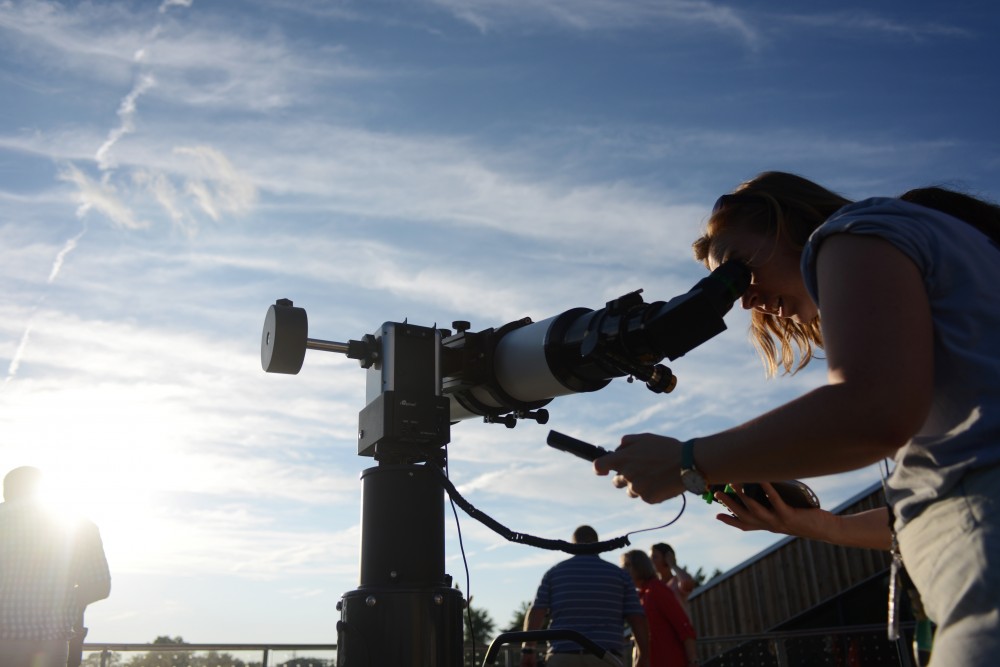 Sarah Komperud dials in a telescope from a cell phone to connect with the setting sun, with the goal of viewing sunspots.