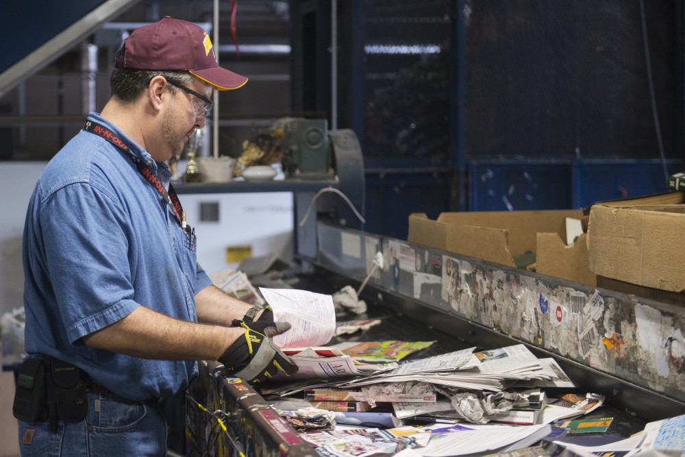 A worker at the Como recycling center sorts out recyclable paper products on a conveyor belt on Friday, July 13. The center will bring about 2,000 organics bins to every building on campus over the course of two years.