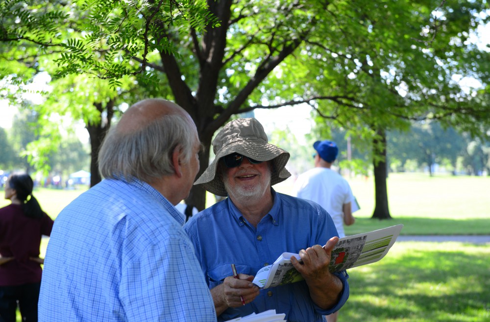 St. Anthony Falls Heritage Board member Ted Tucker reviews two draft designs for Logan Park in Minneapolis on Saturday, July 14 during the twentieth annual East of the River bus tour of neighborhood parks in northeast and southeast Minneapolis. 