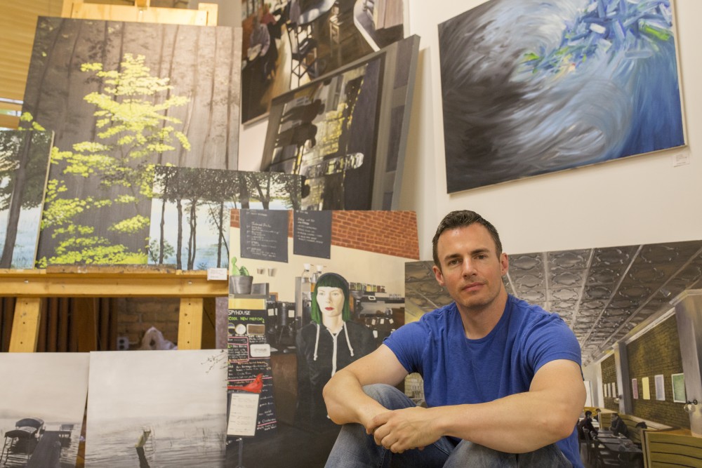 University of Minnesota alum Brendan Kramp poses beside art work he created in his studio at the Casket Art building on Sunday, July, 29. Brendan will be presenting his work at the Uptown Art Festival from August 3-5.