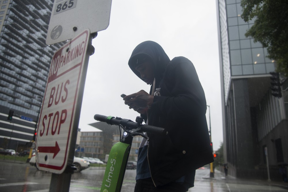 Dayshawn Brown uses his phone to pay for a ride on a Lime electric scooter in downtown Minneapolis. 