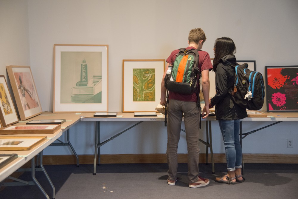 Two students look at the art available to rent on Wednesday, Sept. 19, at Weisman Art Museum. The museum held an art rental event where students could study, eat snacks and find affordable art to rent or purchase. 
