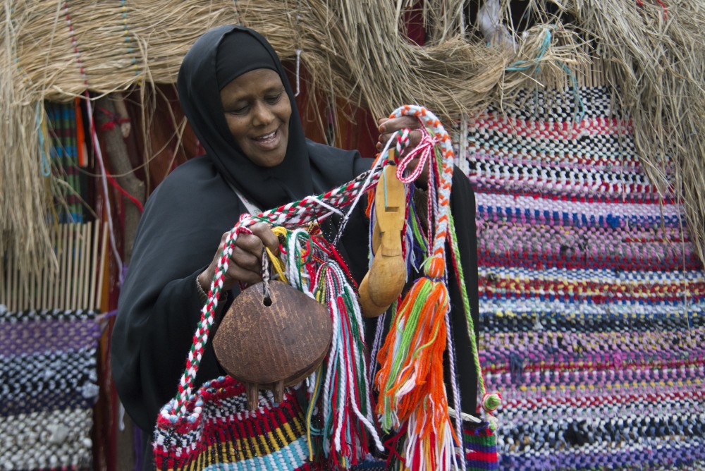 Fatuma Halki holds different types of traditional Somali weaving, camel bells and a spoon from her bag in front of the Somali House on Thursday, Sept. 27 in Minneapolis.  Halki does much of the weaving herself.