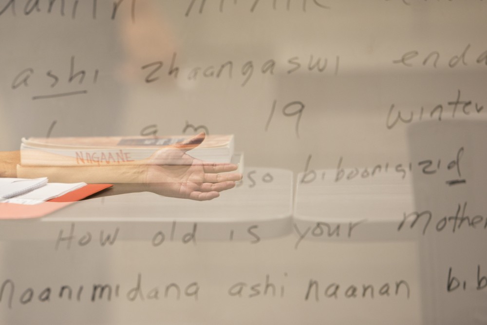 In a multiple exposure image, Anishinaabe Language Instructor Gabe Desrosiers extends his hand toward a white board with written Native American language next to one of the texts required for his class on Wednesday, Oct. 3 at the University of Minnesota-Morris campus. The Anishinaabe program at Morris follows a 2-year cycle, so students must start in the semester that offers the first level, which comes every four semesters.