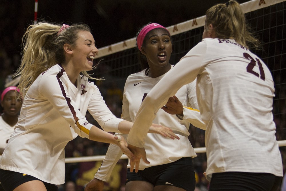 Senior Samantha Seliger-Swenson, left, and sophomore Stephanie Samedy celebrate with redshirt sophomore Regan Pittman after she earned a point during the game against the Northwestern Wildcats on Saturday, Oct. 13. The Gophers beat Northwestern in all three sets.