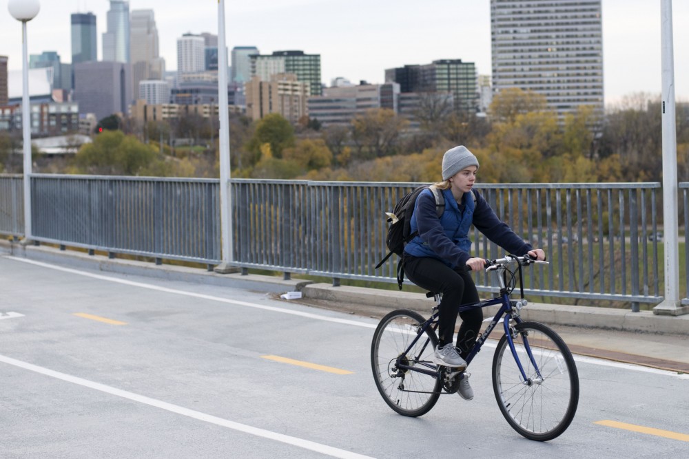 A biker is seen on the Washington Avenue Bridge on Thursday, Nov. 1. The Minnesota Student Association is partnering with Parking and Transportation Services to encourage people to wear helmets while biking. 