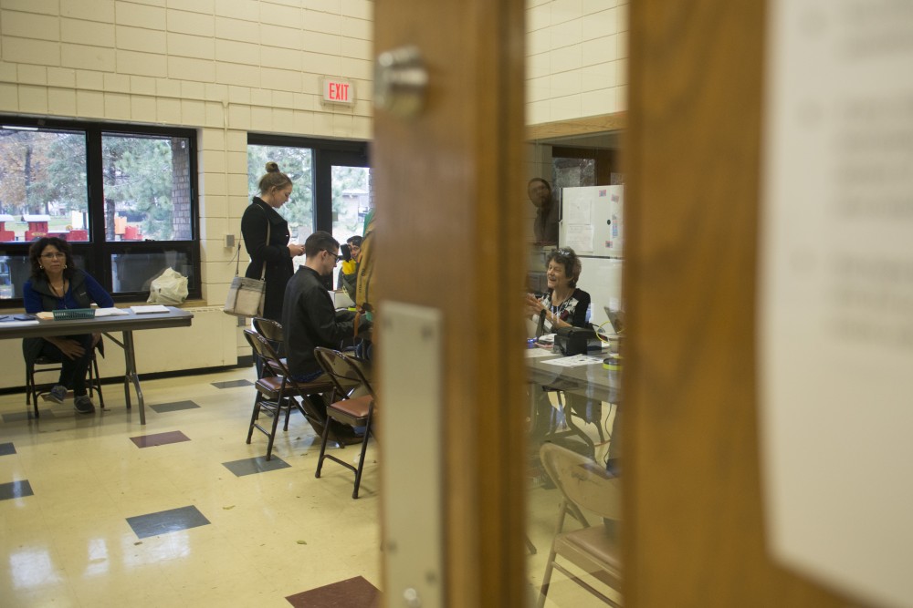 Election Judge Helen Torrens helps a voter through a window at the Van Cleve Park polling place on Tuesday, Nov. 6.