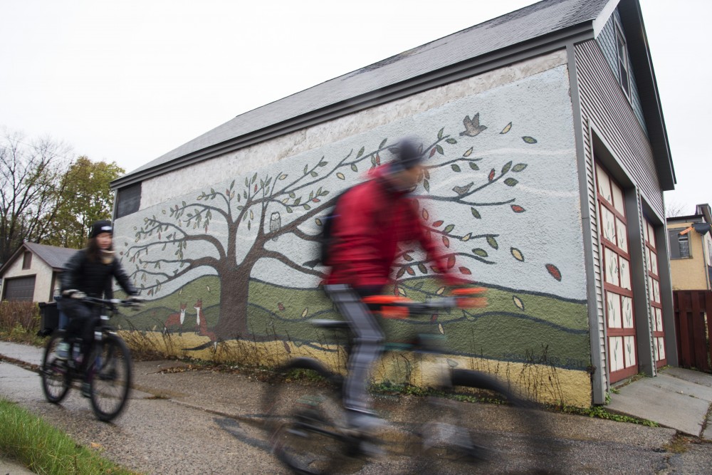 Bikers pass by a piece of alley art on Sunday, Nov. 4. The ride, hosted by the Minneapolis Alley Initiative for Neighborhood Stimulation, features public art in the Longfellow & Powderhorn neighborhoods. The organization keeps a map online for others for follow on their own time. 