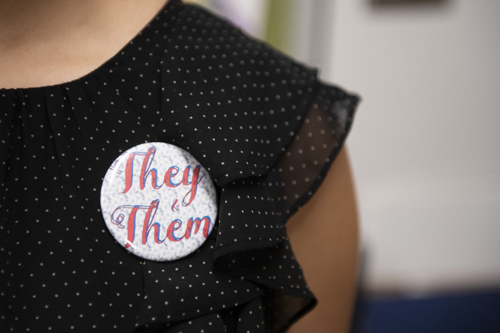 Haruka Yukioka, relations manager of the Queer Student Cultural Center displays their they/them pronoun pin in Coffman Union on Tuesday, Oct. 30. 