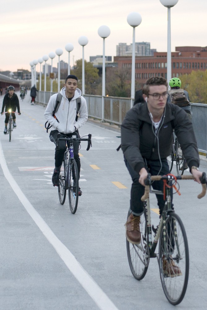 Bikers are seen on the Washington Avenue Bridge on Thursday, Nov. 1. The Minnesota Student Association is partnering with Parking and Transportation Services to encourage people to wear helmets while biking. 