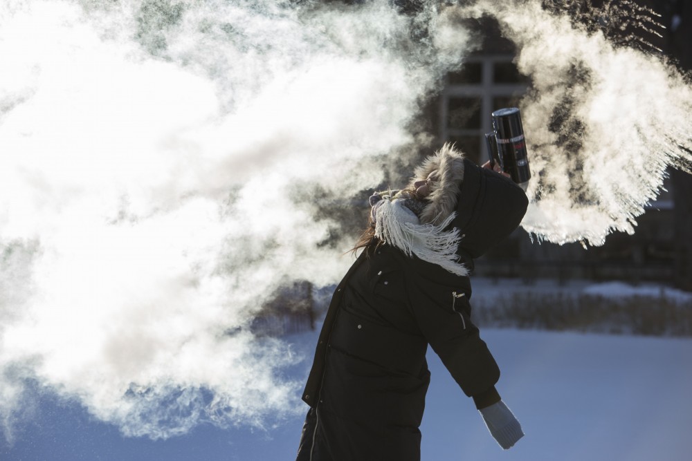 Electrical Engineering sophomore Yilia Yang throws hot water into the air to watch it freeze on Wednesday, Jan. 31 in the East Bank Mall. Yang had the day off because classes were cancelled due to extremely low temperatures.