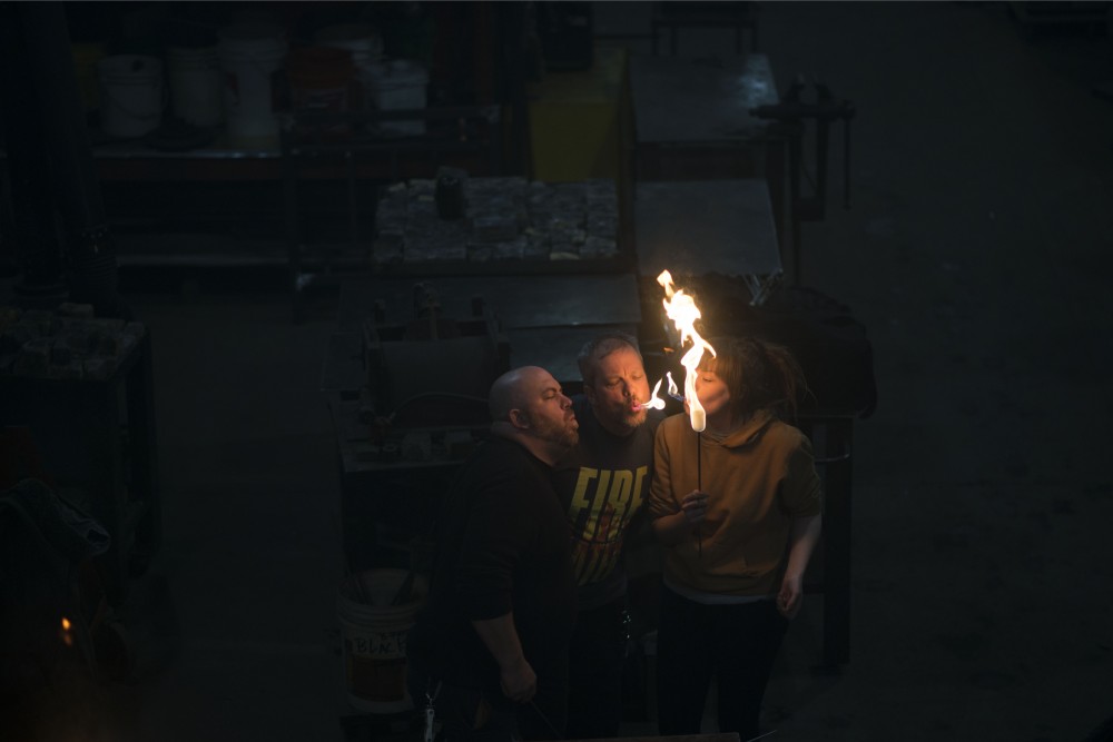 Joshua Nelson, left, Troy Reem, center, and Jenifer Gilpatrick, right, do a mouth transfer of fire during a fire breathing lesson at the Minneapolis Fire Collective on Friday, March 8.