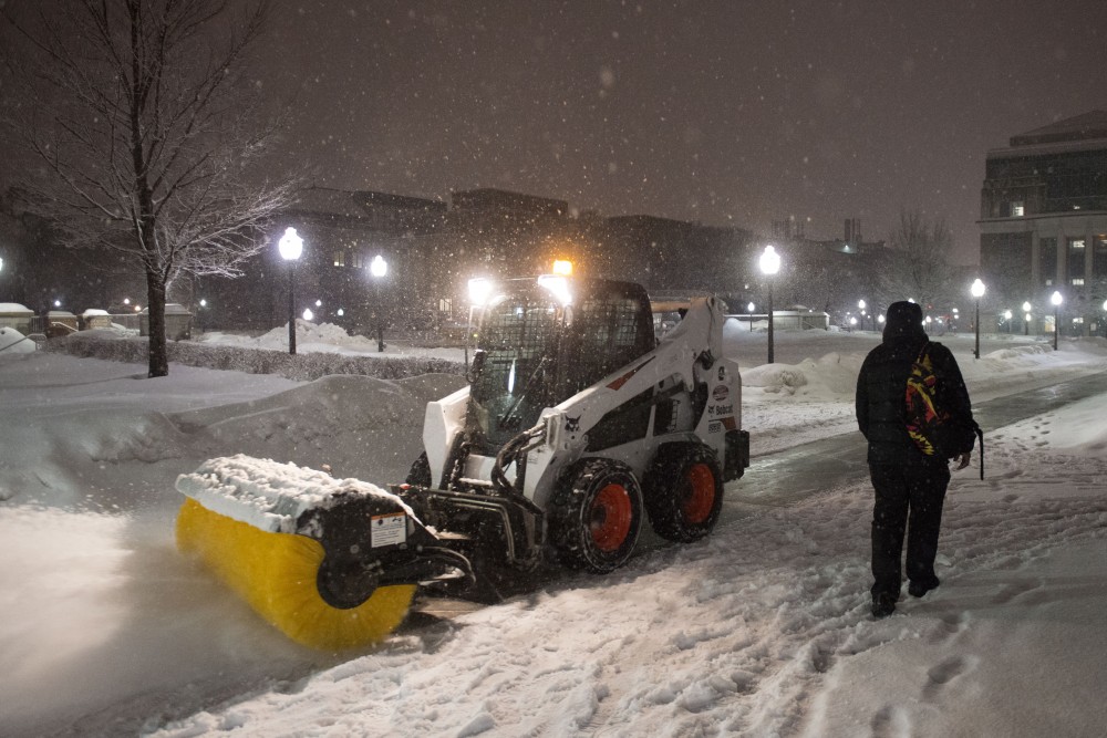 University Landcare blows snow off the path in front of Coffman Union on Saturday, March 9.