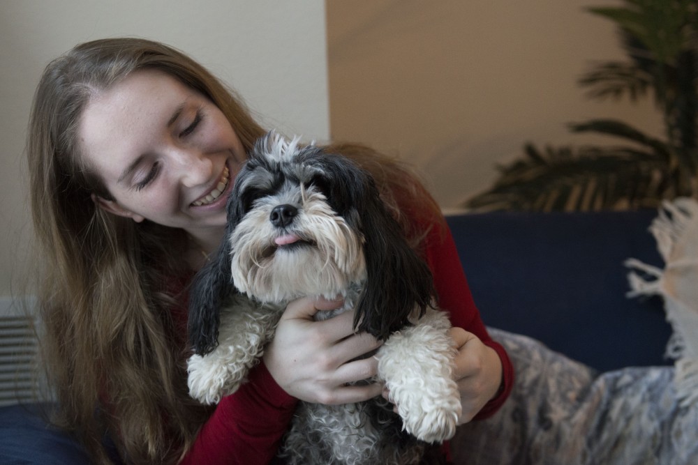 Sophia DeGarmo plays with her dog, Riley, in her apartment on Friday, March 8. Riley is a registered emotional support animal who helps DeGarmo manage her mental health. 