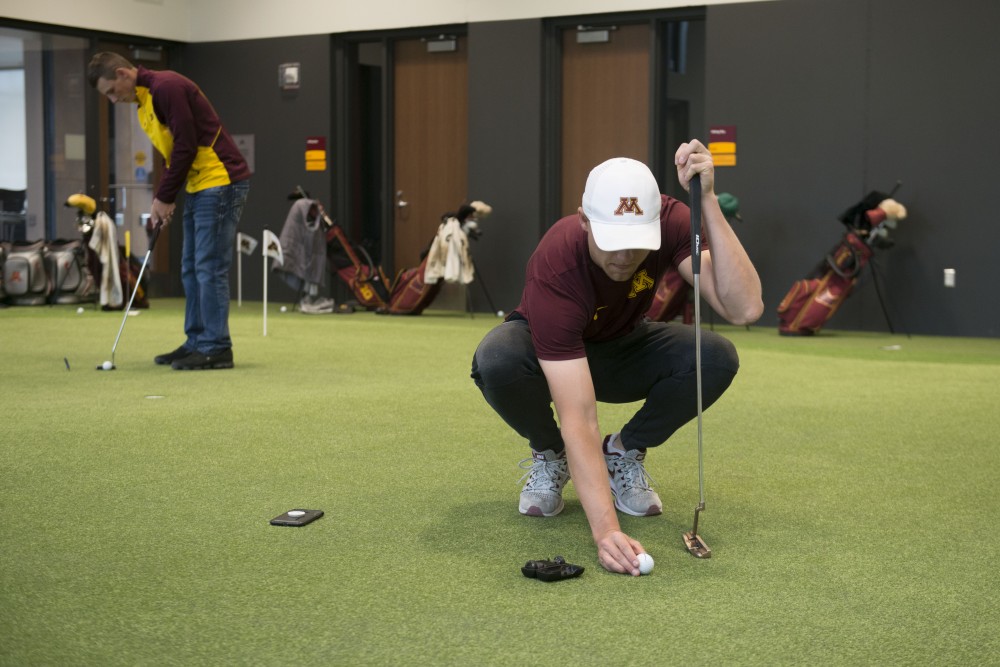 Junior Thomas Longbella lines up a shot on the putting green in the new indoor golf training facility on Monday, April 1. The facility borders the Les Bolstad Golf Course and allows for practice throughout winter months. 