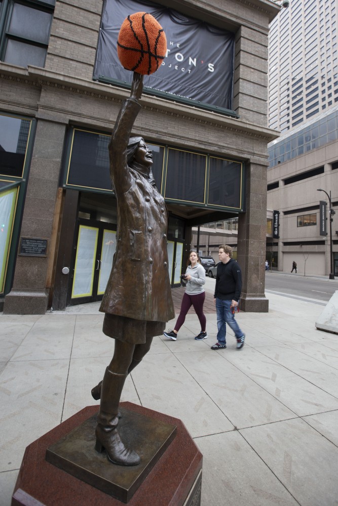 Passersby eye the Mary Tyler Moore Statue on Friday, April 5 as they head toward the Tip-Off Tailgate on Nicollet Mall.