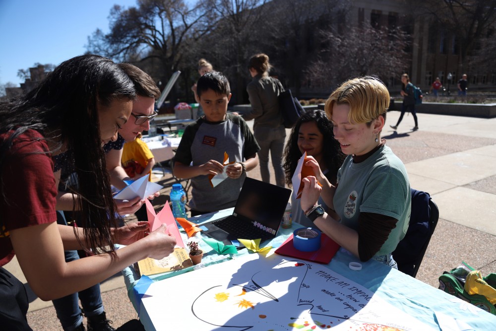 Isabel Voigt demonstrates how to make paper butterflies at the Environmental Justice Earth Day celebration in Northrop Mall on Friday, April 19.