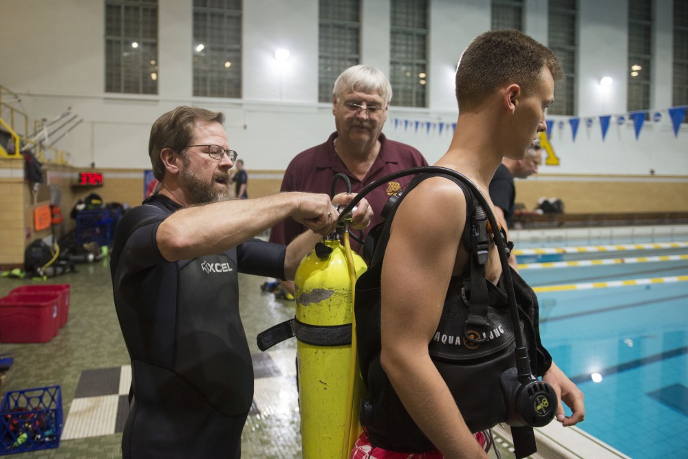 Instructors Shawn Jones, left, and Bob Karl, center, help C.J. Kenney with his air tank on Wednesday, April 17 during scuba diving class in Cooke Hall.