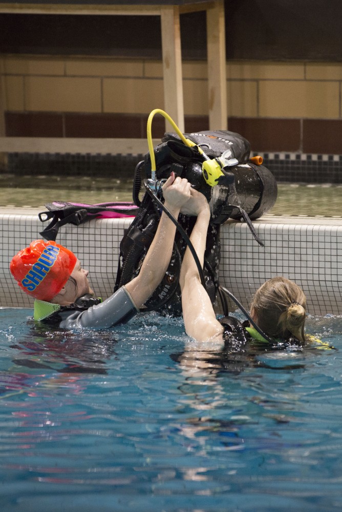 Students remove their tanks and work together to lift the gear out of the pool during scuba diving class on Wednesday, April 17 in Cooke Hall.