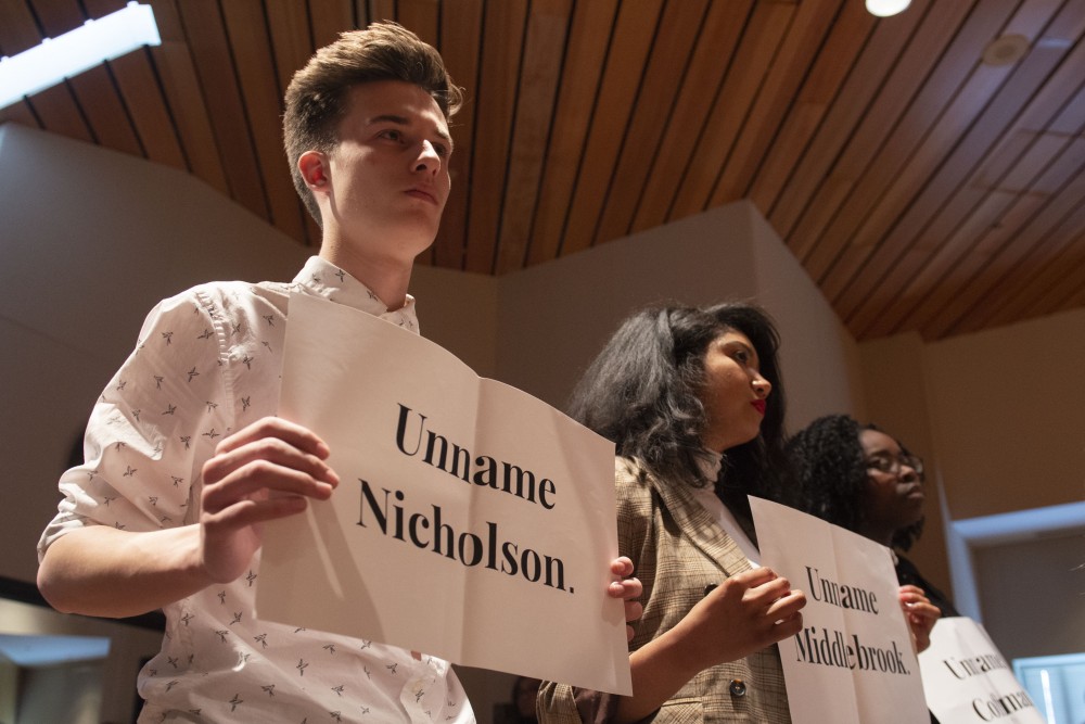 Student demonstrators hold up signs in protest of the Board of Regents position on building renaming during the special session on Friday, April 26. The board voted against the renaming of four buildings on campus after more than a year of community discussion on the issue. 