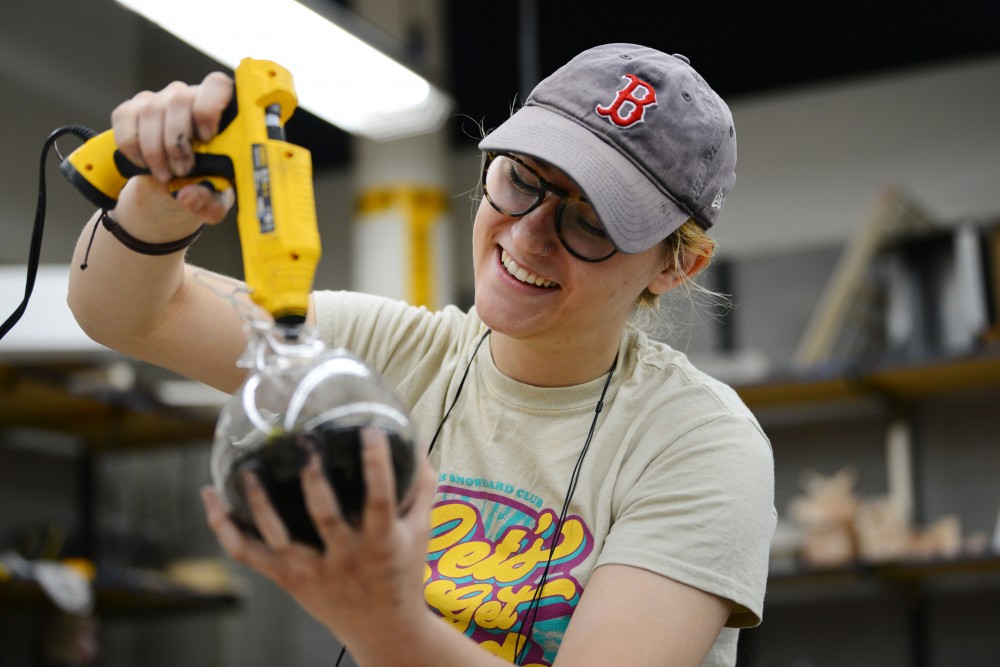 Engineering freshman Elena Lyons-Macatee works on her final project for sculpture class in the Regis Center for Art on Wednesday, May 1. Lyons-Macatee is making an hourglass out of the glass from an Erlenmeyer flask. The sculpture is a representation of the environmental activist group Extinction Rebellions logo.  