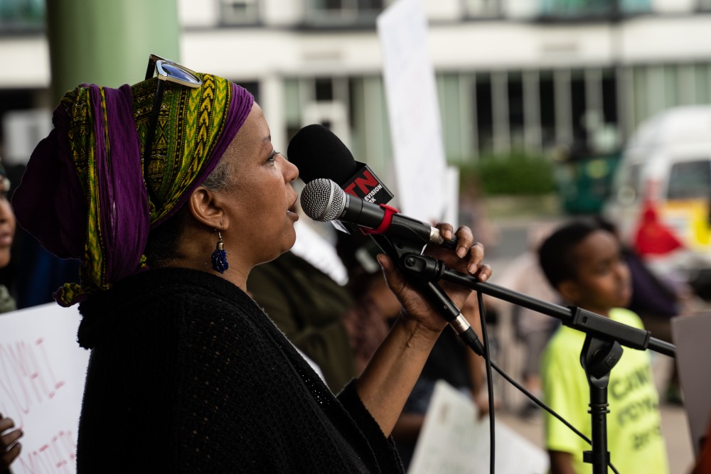 Ladan Yusuf speaks to a crowd protesting the development of an African Village in the Cedar Riverside area at a protest organized by the Somali Mothers of MN at Currie Park on Sunday, July 7.