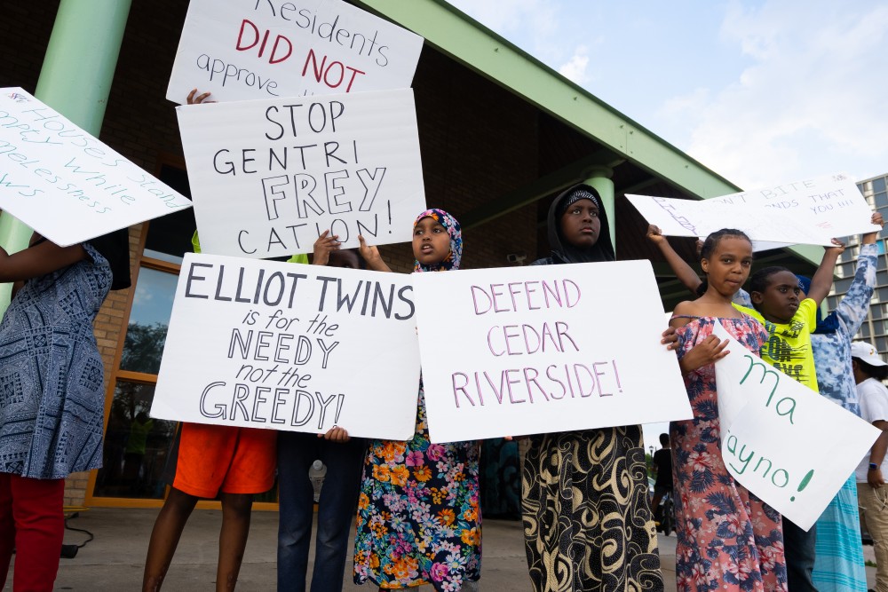 Youth hold signs protesting the development of a mall in the Cedar Riverside area at a protest organized by the Somali Mothers of MN at Currie Park on Sunday, July 7.