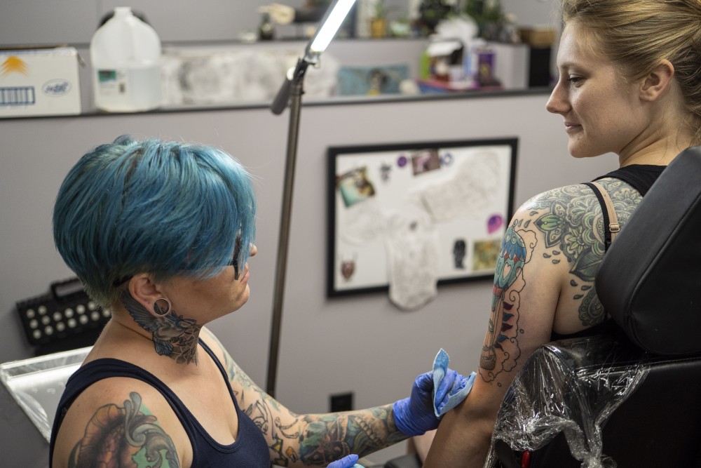 Artist Amo Azure wipes ink off Jen Bautchs arm on Tuesday, July 9 at Jackalope Tattoo in Minneapolis. 
