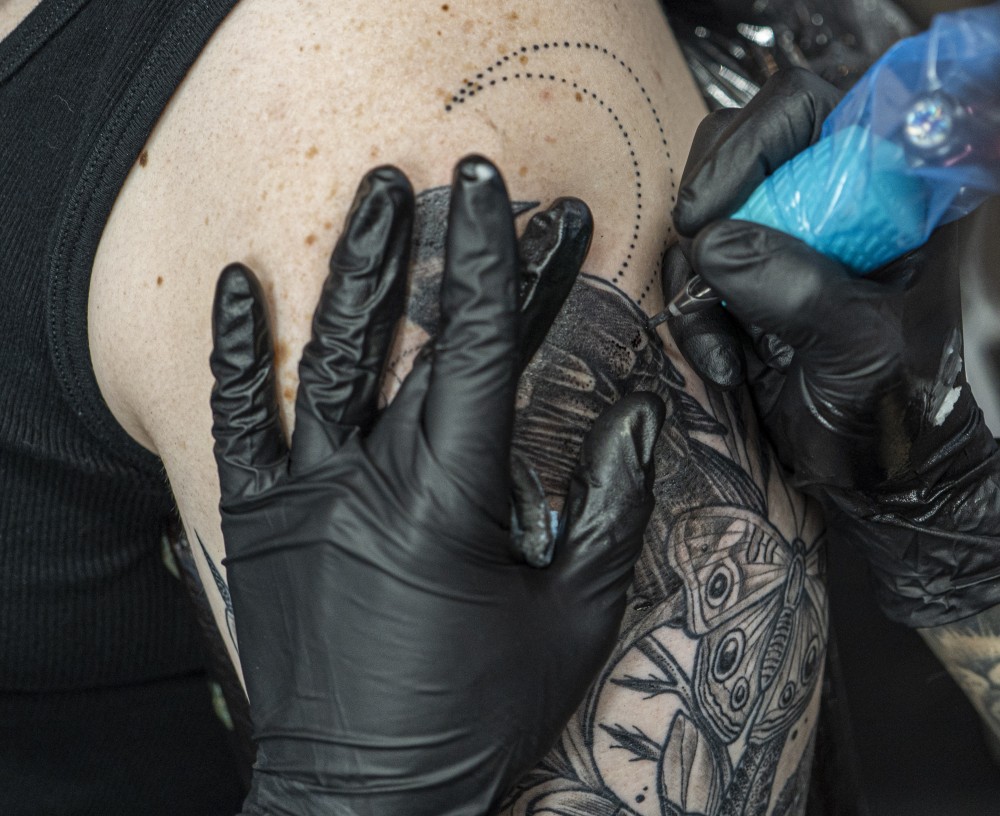 Owner Emi Nijiya tattoos a red winged black bird on Nia Rathbones arm on Tuesday, July 9 at Jackalope Tattoo in Minneapolis. Jackalope Tattoo is exclusively run by female or non-binary artists.