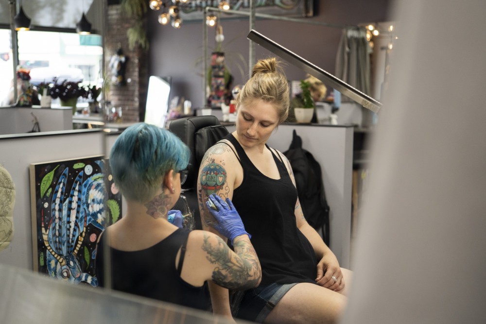 Artist Amo Azure wipes ink off Jen Bautchs arm on Tuesday, July 9 at Jackalope Tattoo in Minneapolis. Jackalope Tattoo is ran entirely by female and non-binary artists.
