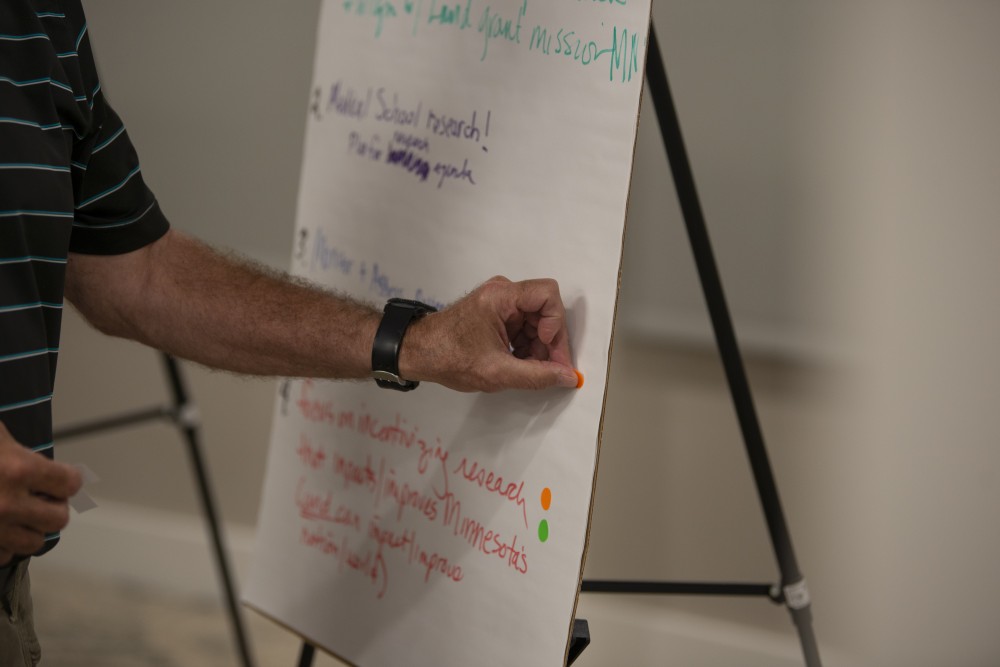 Board Chair Ken Powell puts a sticker on one of his favorite ideas for the several pillars of the University that were discussed at the regents retreat on Friday, July 12 in Faribault. 