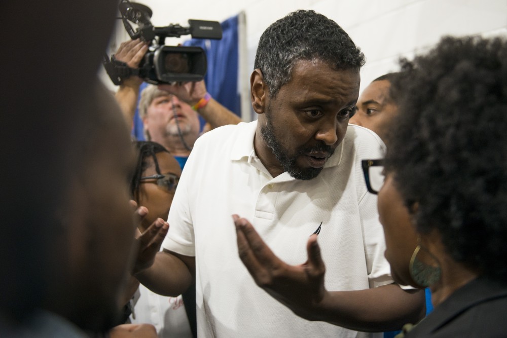 City Council Representative Abdi Warsame converses with a member of the crowd at Pillsbury United Communities Brian Coyle Center on Friday, Aug. 30. The listening session was discontinued following demonstrations by protestors in the crowd.