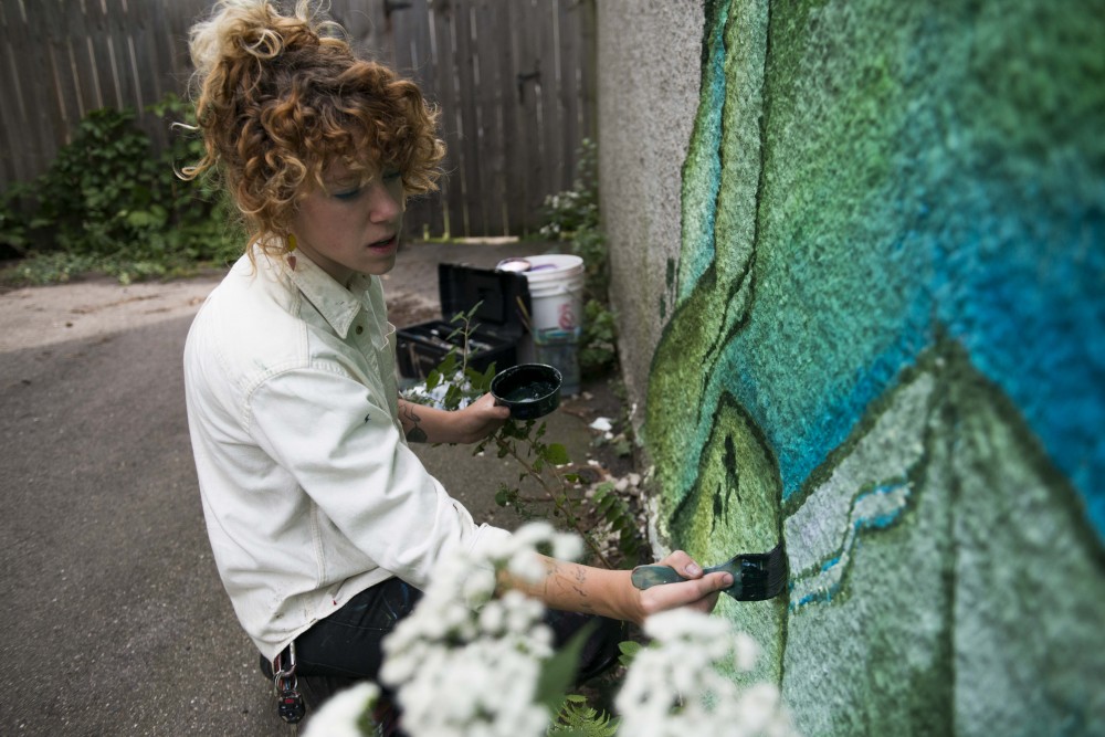 Liv Novotny paints a mural on the side of their garage in Minneapolis on Saturday, Sept. 7.