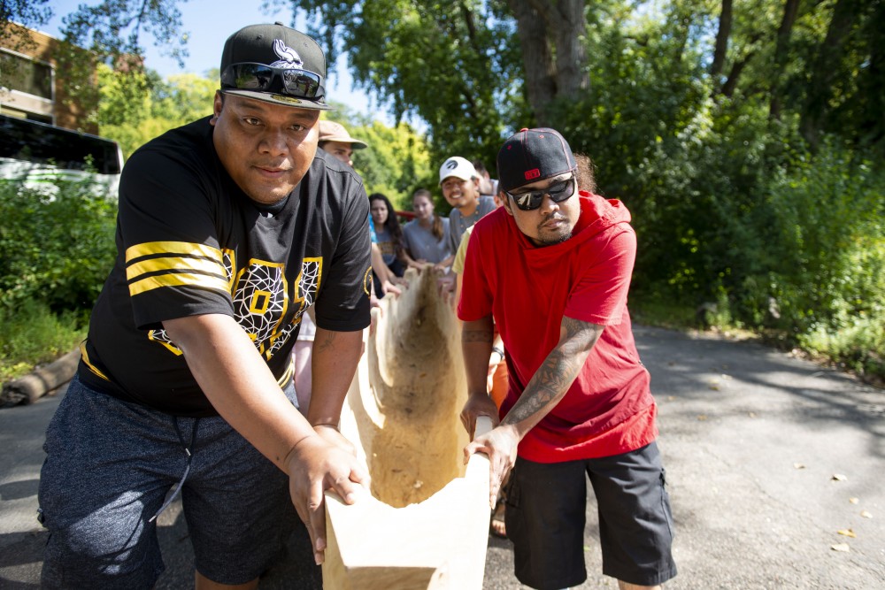 Comunity members carry a newly made canoe to the banks of the Mississippi River at the “Navigating Indigenous Futures” event held on the East River Flats on Thursday, Sept. 19, 2019. (Jack Rodgers / Minnesota Daily)