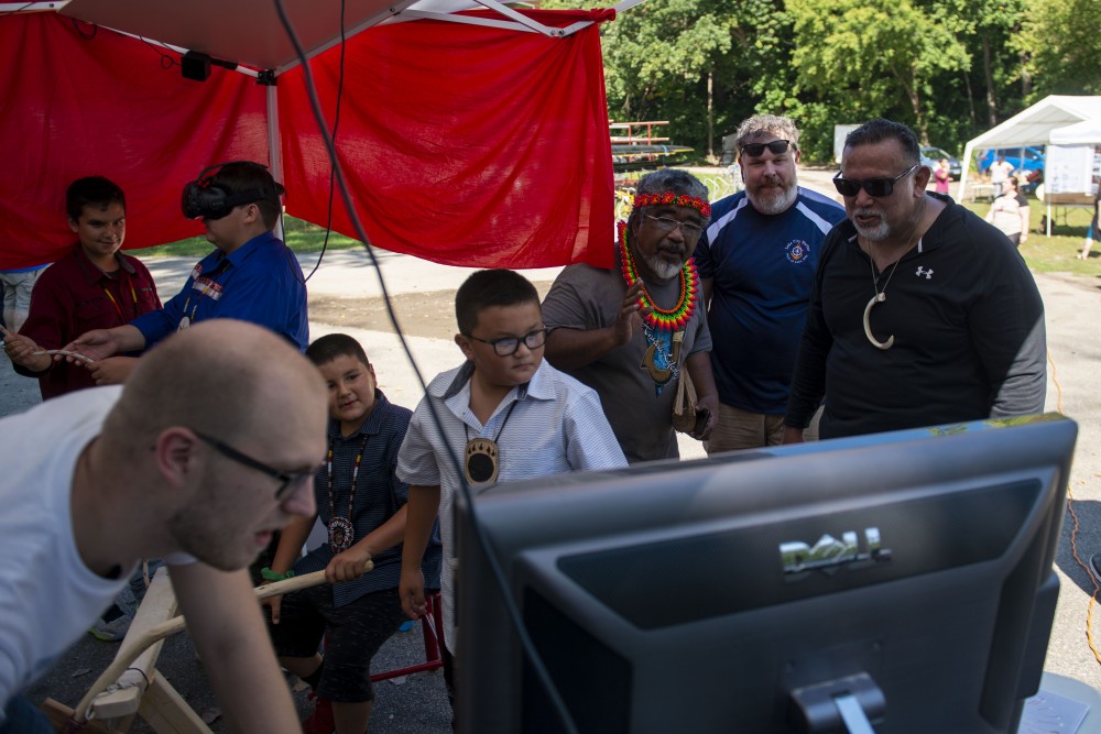 Seth Johnson, left, demonstrates a virtual reality canoe simulator at the “Navigating Indigenous Futures” event on Thursday, Sept. 19, 2019. The simulator is part of a project led by Daniel Keefe, who stands back, center, to help further connect indigenous communities.