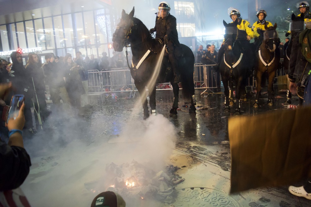 Make America Great Again hats on fire are extinguished outside of the Target Center in downtown Minneapolis following a rally held by President Donald Trump on Thursday, Oct. 10. 