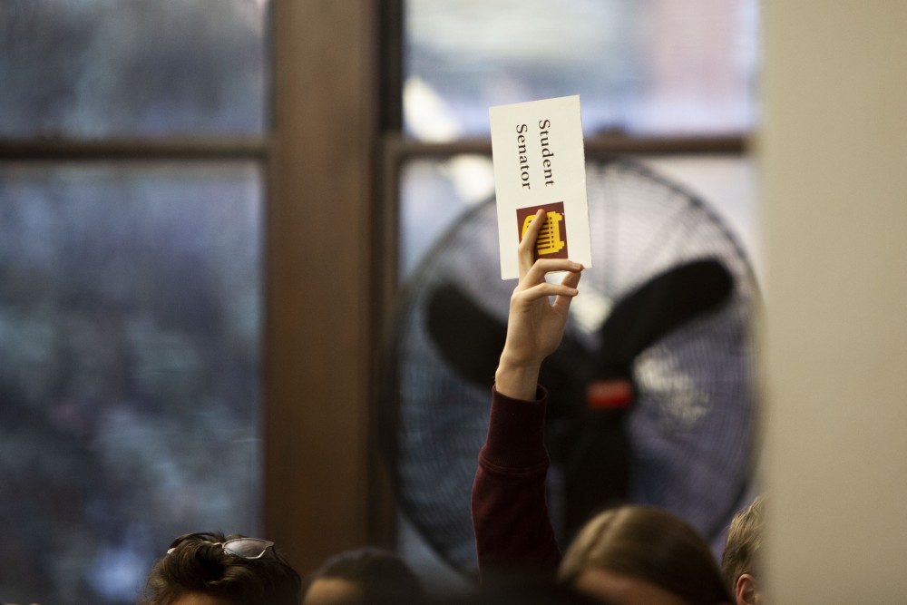 A student senator raises their placard to propose a point of order in Fraser Hall on Tuesday, Oct. 22. 