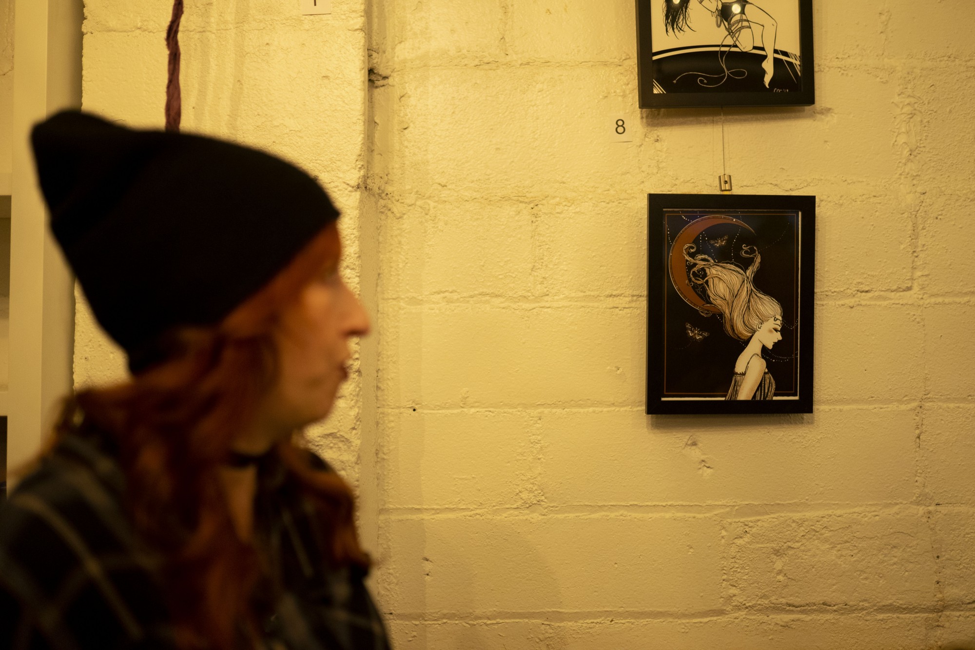 Courtney Thomas, one of the three artists whose work was displayed at the “Making Strange Microshow, walks past a piece on display at the Twin Cities Distillery on Friday, Nov. 8. Much of  Thomas inspiration comes from themes of female empowerment. 