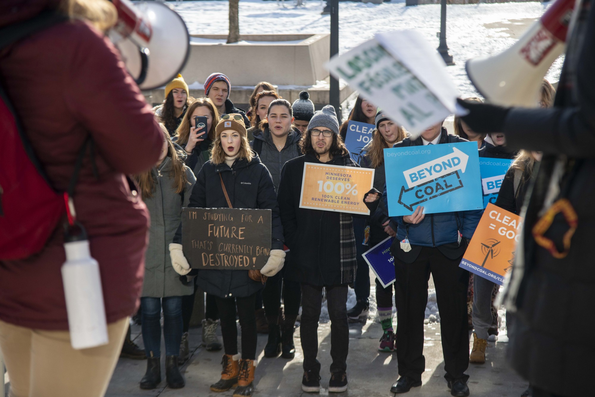 Savannah Wery, left, and Katherine Schmid, right, speak to protesters participating in the UMN Climate Strike outside of Coffman Union on Friday, Dec. 6. Those in attendance criticized the University’s policies on fossil fuel usage.