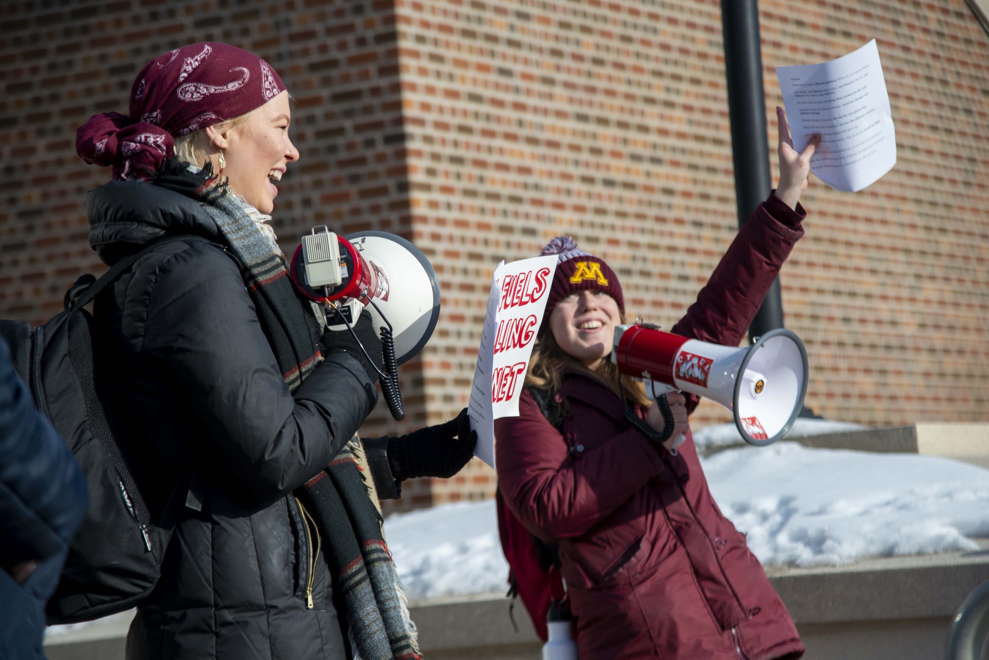 Savannah Wery, right, and Katherine Schmid, left, speak to protesters participating in the UMN Climate Strike outside of Coffman Union on Friday, Dec. 6. Those in attendance criticized the University’s policies on fossil fuel usage.