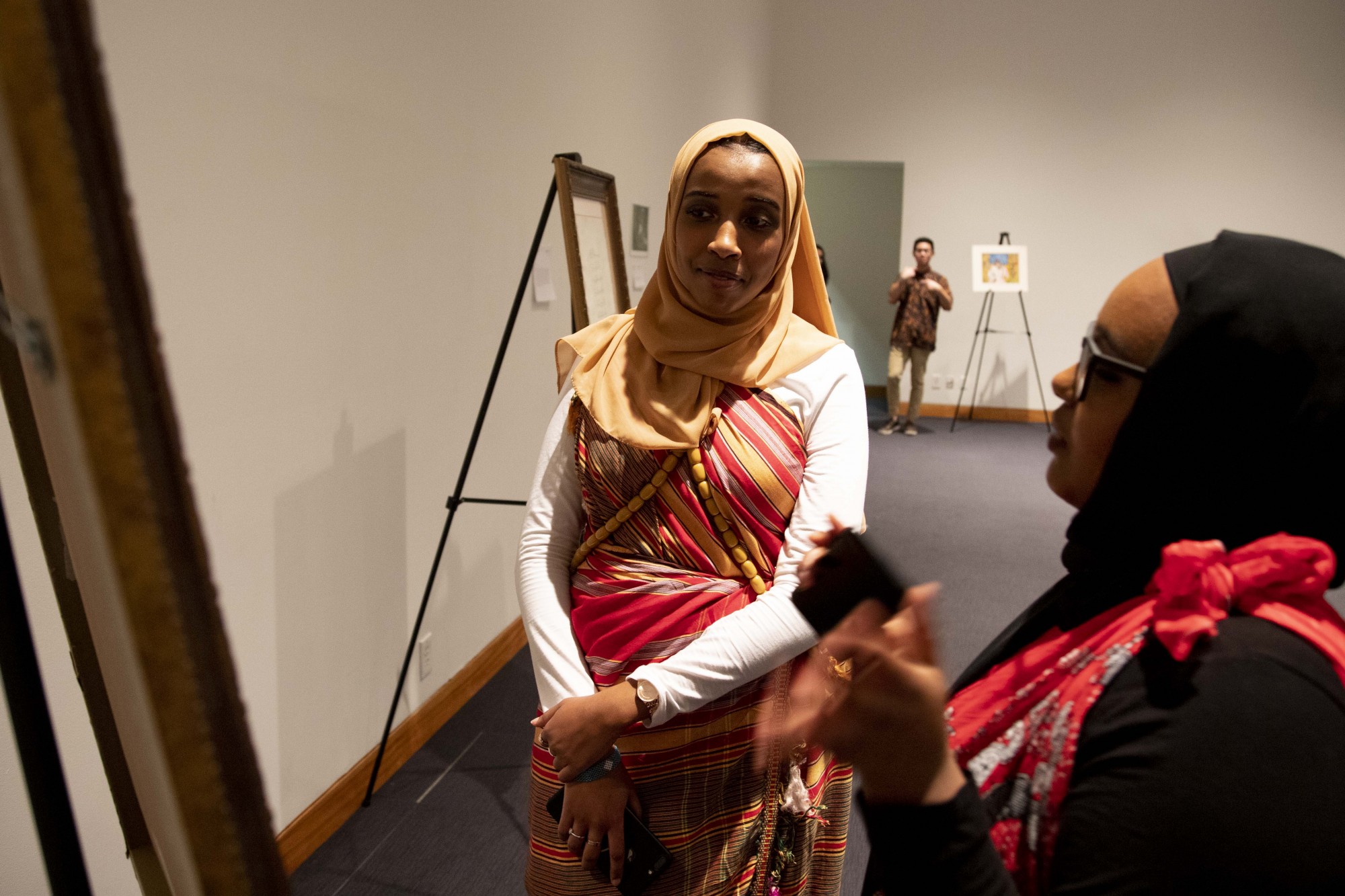 Ruwayda Mohamed, left, and Zahra Mustafa, right, observe art at the Al-Madinah Cultural Centers Do It For the Culture Gala at the Weisman Art Museum on Friday, Dec. 6. 