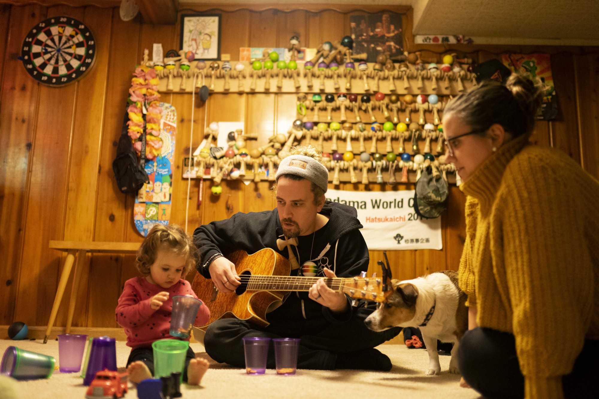 Jorgenson, plays guitar for his daughter, Emma, left, and wife, Alex, right, in his home on Monday, Dec. 2 before he leaves for a weeklong trip to judge internationally. Seen behind him is a fraction of the Kendamas Jorgenson has collected over the years. 