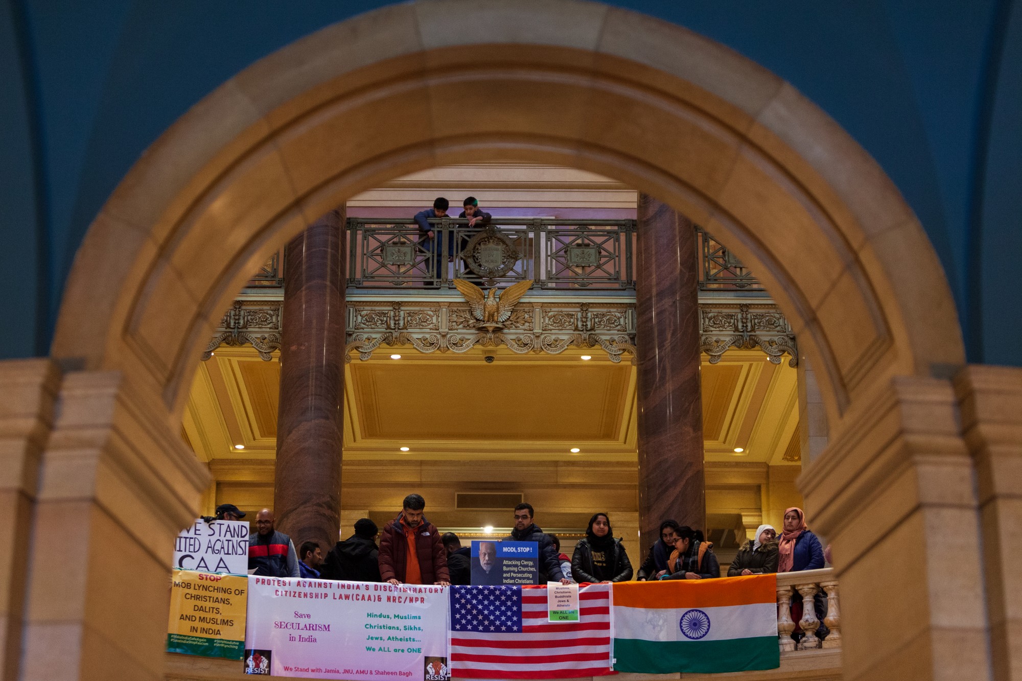 Protestors drape Indian and U.S. flags over the balcony of the rotunda at an event opposing Indias recent passage of the Citizenship Amendment Act at the Minnesota State Capitol Building on Sunday, Jan. 26. This legislation offers Indian citizenship to refugees of several religious groups, but does not apply to Muslims, despite their making up nearly 15% of the Indian population. (Kamaan Richards / Minnesota Daily)