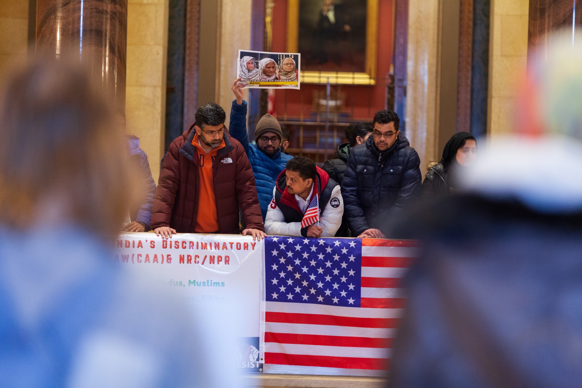 Protestors drape a U.S. flag over the balcony of the rotunda at an event opposing Indias recent passage of the Citizenship Amendment Act at the Minnesota State Capitol Building on Sunday, Jan. 26. This legislation offers Indian citizenship to refugees of several religious groups, but does not apply to Muslims, despite their making up nearly 15% of the Indian population.