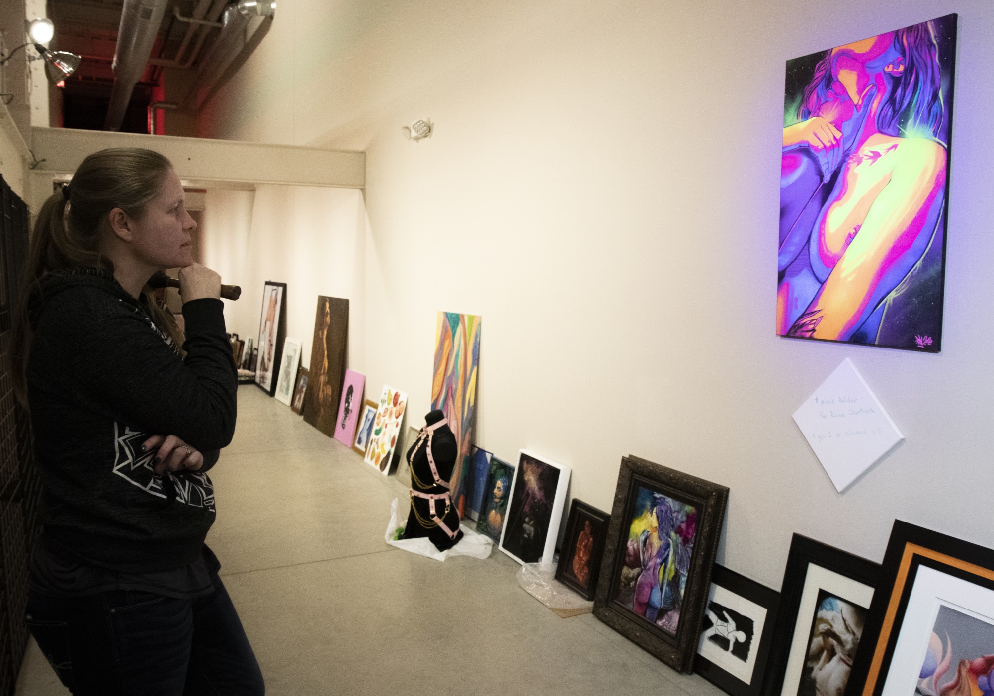 Angel Hawari evaluates the placement of a painting during setup for Safeword: An Erotic Art Show at the A-Mill Underground Museum on Saturday, Feb. 8.