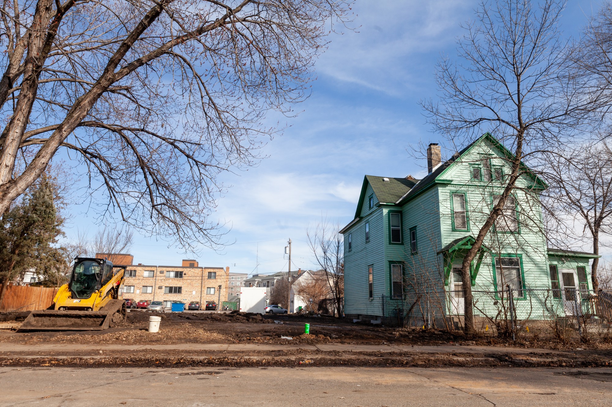 Construction equipment stands ready on an empty plot beside homes on Erie Street Southeast on Friday, March 13. Several homes on the block are set to be demolished as part of a broad plan for the future clinical campus facility.